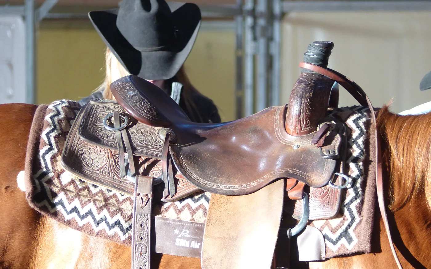 Verzierte Westernsättel mit Satteldecken und Cowboyhut auf Sattelböcken einer Reitsportmesse